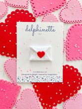 Load image into Gallery viewer, delphinette handmade felt little girl/baby girl hair accessory - a little white felt enveloped sealed with a little red heart that can be customized as a hair clip, headband or hair tie. Handmade in Canada.
